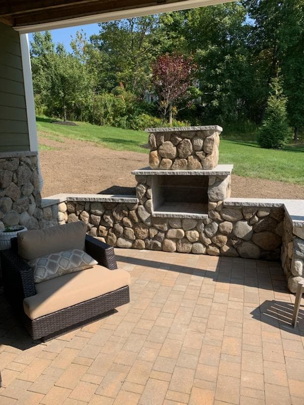 Fieldstone outdoor fireplace with seat walls on a paver patio