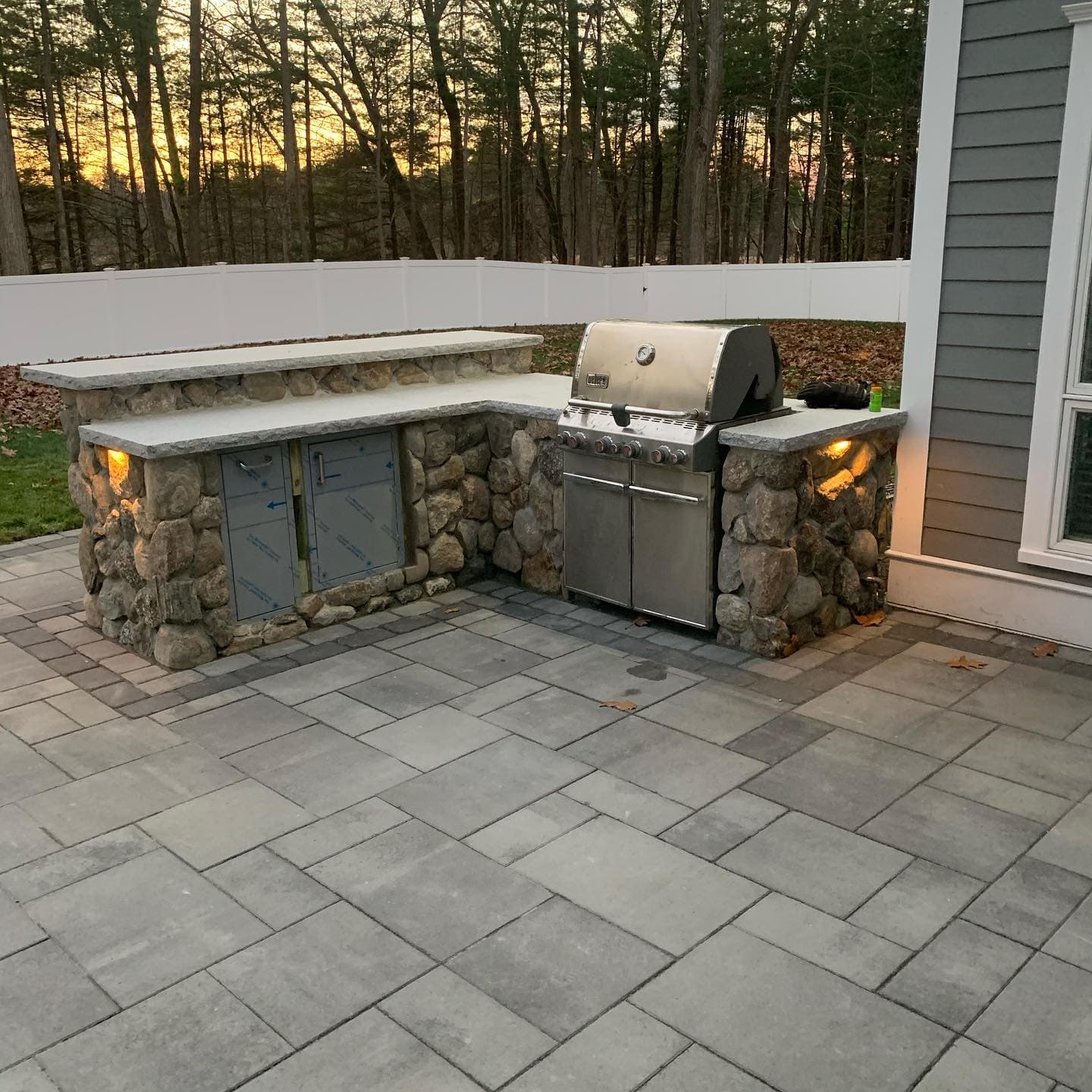 Fieldstone outdoor kitchen at dusk with warm under-counter lights