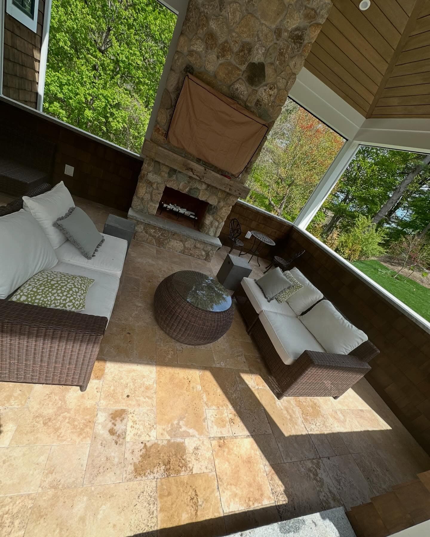 Covered porch with travertine floor and a stone fireplace