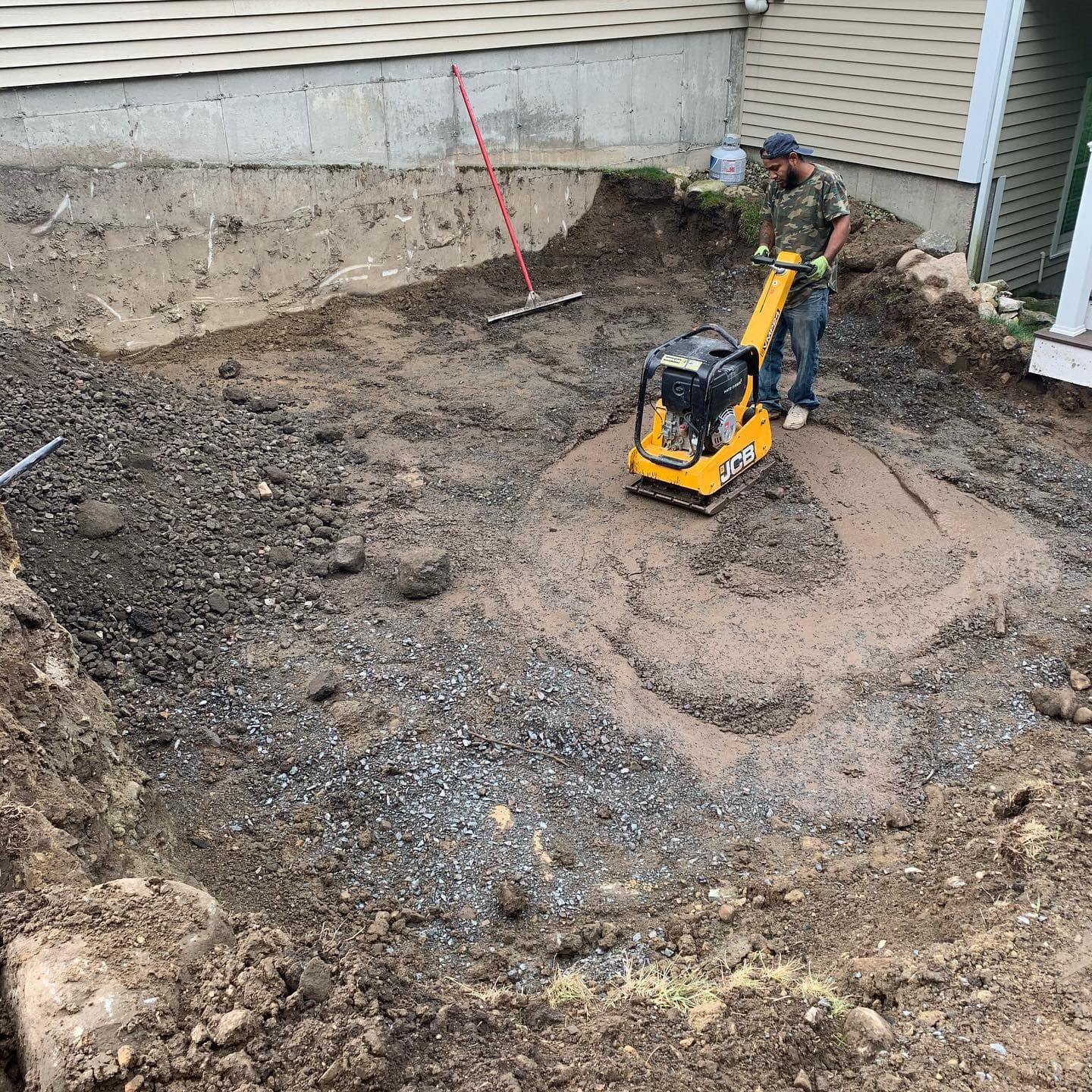 Plate compactor compacting the crushed-stone base for a new patio